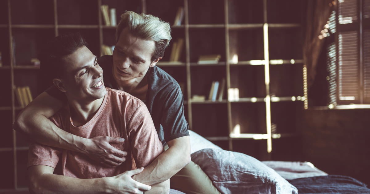 Due uomini abbracciati dinanzi a una libreria per sottolineare l'importanza dei libri d'amore gay.