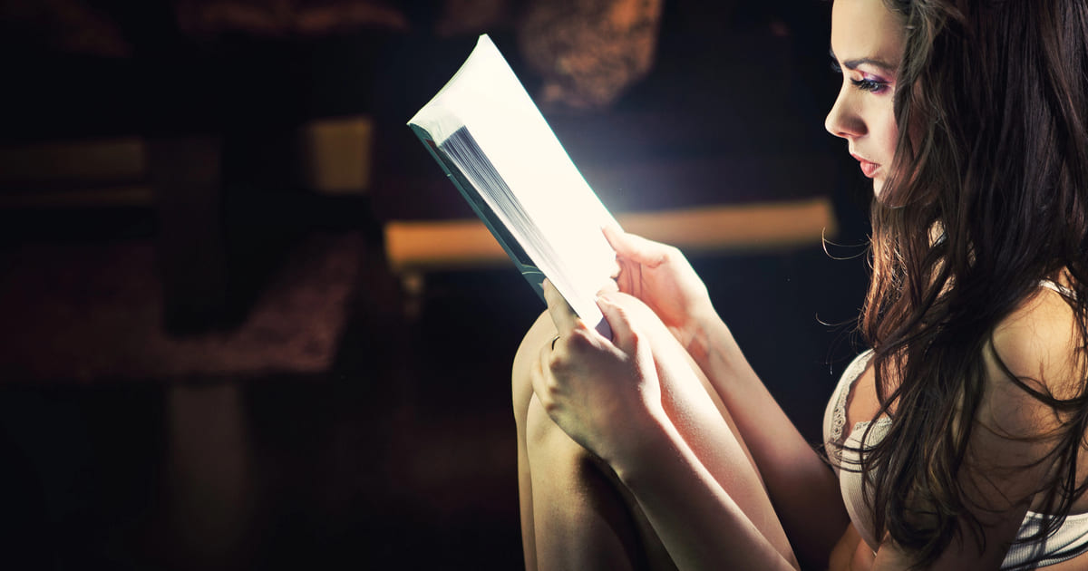 Giovane donna seduta legge uno dei libri fantasy per adolescenti che sembra emettere una luce