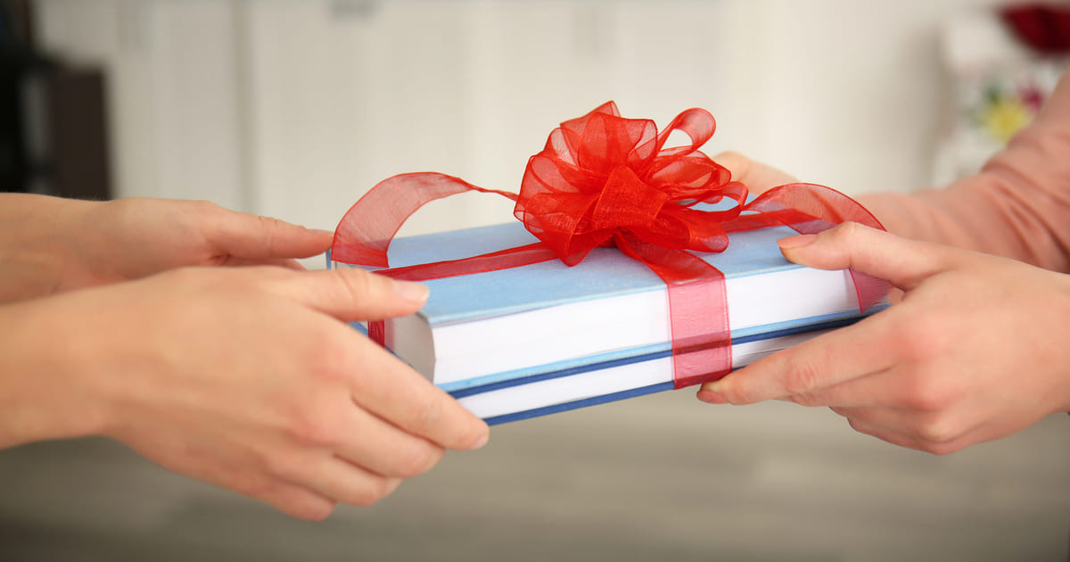 Due libri infiocchettati che vengono donati come regali letterari e pssano da una mano all'altra