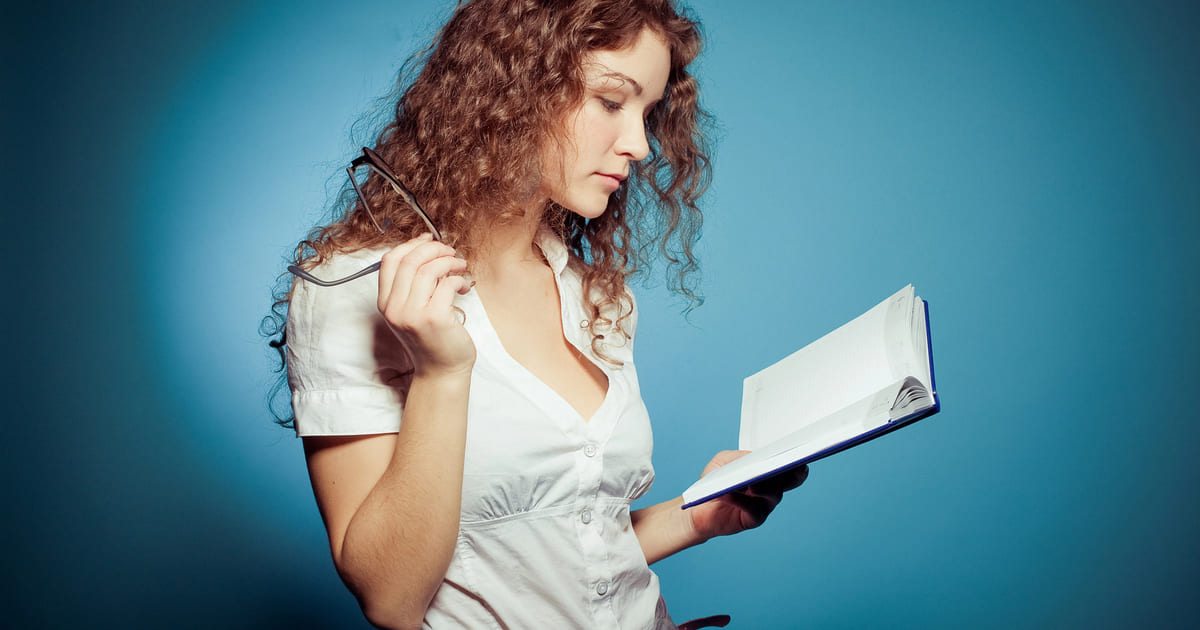 Esempio di come scrivere un romanzo: una ragazza con i capelli lunghi ricci rossi legge un libro e si sofferma a pensare