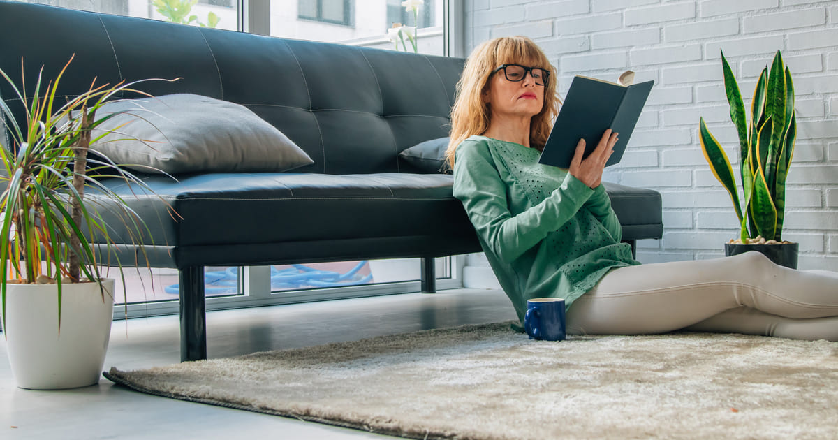 una donna seduta a terra e poggiata al divano si dedica a letture emozionanti