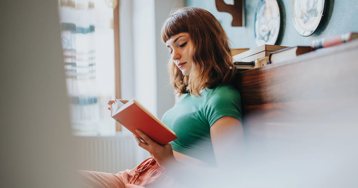 Assaggi di lettura: donna con maglietta verde legge un libro dalla copertina rossa