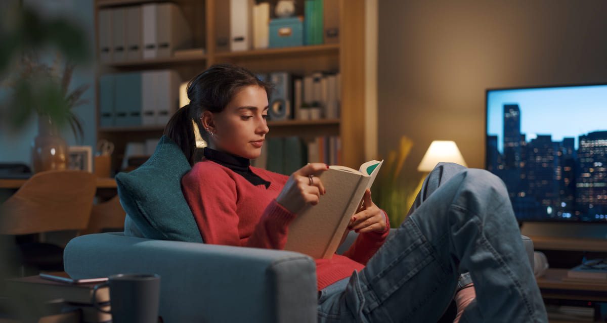Donna che legge un libro con storia di vita in un ambiente accogliente e silenzioso