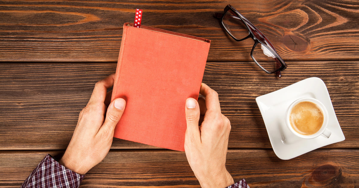 DNF libri - libro con segnalibro chiuso su tavolo di legno con caffè e occhiali