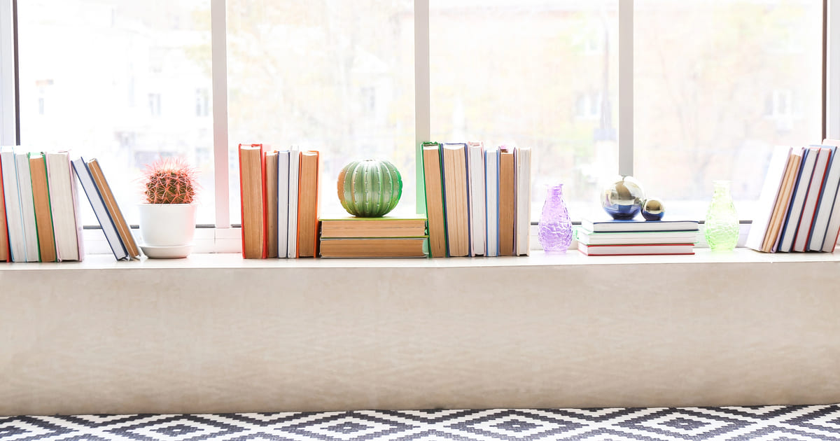 Libri organizzati sul davanzale di una finestra in una casa piccola con luce naturale - Dove mettere i libri in una casa piccola