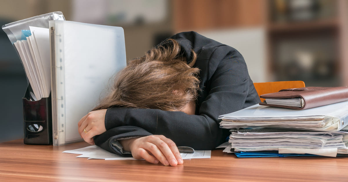 Frasi sul burnout emotivo - Donna esausta alla scrivania simbolo di burnout emotivo e stress lavorativo