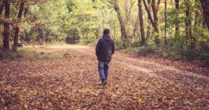 Uomo di spalle cammina in un bosco autunnale – frasi sulla nostalgia malinconica