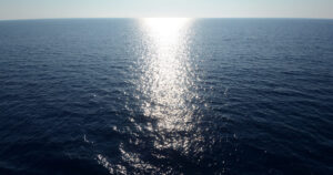 Oceano aperto con riflesso del sole sull'acqua, immagine per frasi sull'oceano e l'infinito