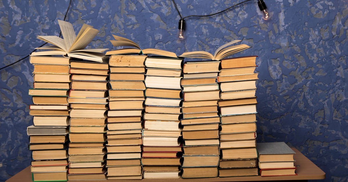 Il punto lettura: pile di libri aperti su un tavolo con luci sospese