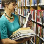 Lettrice in libreria con una pila di libri: aggiornamenti lampo di lettura