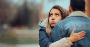 Ragazza con espressione dubbiosa durante un abbraccio, immagine che illustra le frasi sull'amicizia tossica
