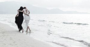 Due donne abbracciate camminano sulla riva del mare — romanzi sulle sorelle