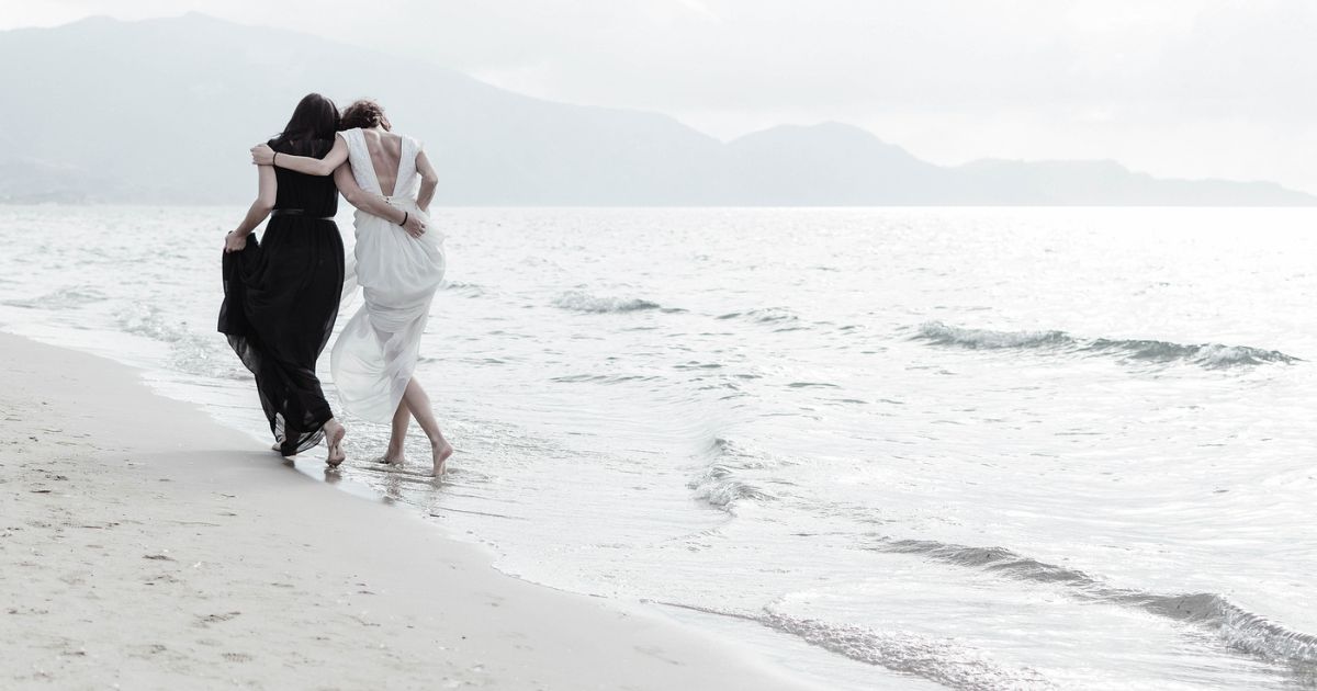 Due donne abbracciate camminano sulla riva del mare — romanzi sulle sorelle