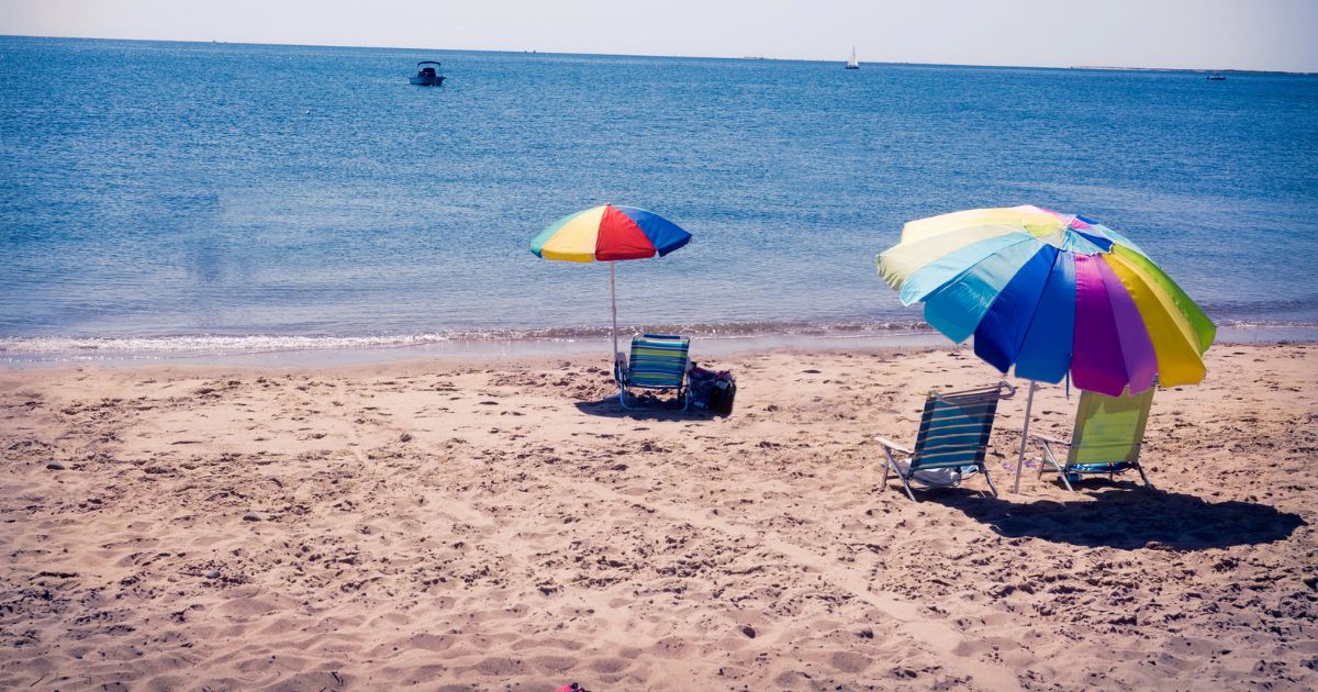 Spiaggia quasi deserta con ombrelloni colorati — immagine per frasi sull'estate che finisce
