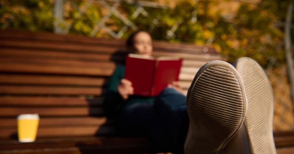 Una persona legge un libro al parco in un momento di relax, spunto per riflettere sulle frasi sulla disconnessione digital