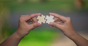 Due mani uniscono un pezzo di puzzle, immagine simbolo delle frasi sulle anime gemelle mancate